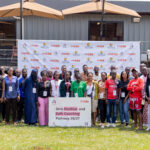 Participants in Cheza’s Girls Positive and Safe Coaching Pathway 26/27 training pose in front of Cheza and TAFISA branding.